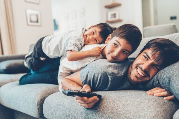 Father and sons enjoying IPTV streaming on a smart TV at home